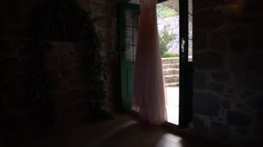 Girişte asılı soluk pembe bir gelinliğin boncuklu korsesi..