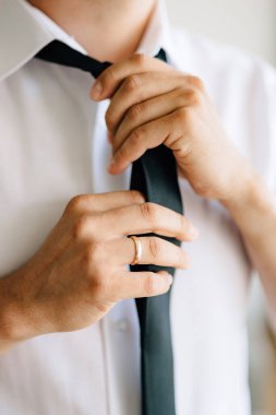 Bir adam düğün hazırlıkları sırasında kravat takar ve kravat bağlar.