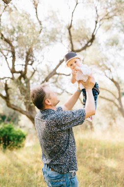 Baba oğlunu kollarına alır ve onu zeytin koruluğunun üstünde tutar.