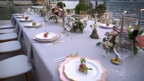 Stół na bankiecie weselnym, ozdobiony kwiatami, świeczniki z płonącymi świecami i młode granaty na molo w Zatoce Kotor — Wideo stockowe