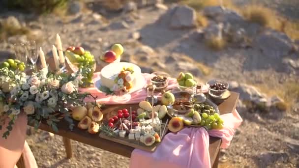 Свадебный стол "шведский стол" с закусками, фруктами, тортом, украшенным розовой тканью, цветами и свечами — стоковое видео