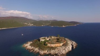 Antik Mamula kalesinin manzarası, ona yakın bir yat ve körfez kıyısı. 