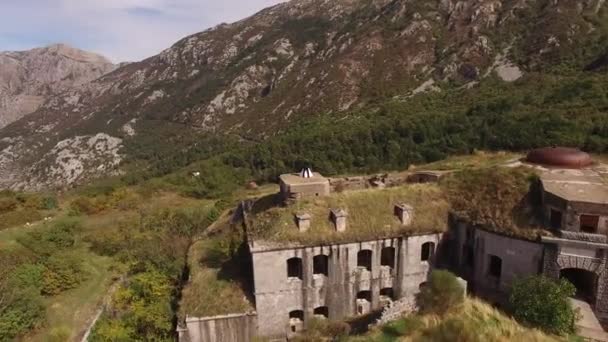 De bruid en bruidegom knuffelen op het dak van het Gorazda fort, achter hen een uitzicht op de baai van Kotor — Stockvideo