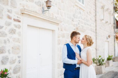 Damat, Perast 'taki güzel beyaz bir evin arka planında geline nazikçe sarılıyor. 