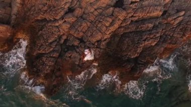 Gelin ve damat deniz kenarındaki kayalıklarda uzanmış, en üst manzarada. 