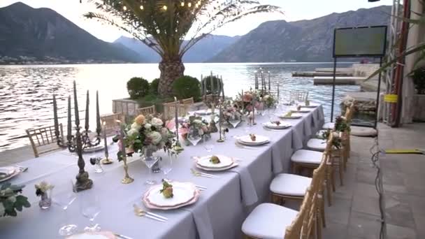 Ett bord vid en bröllopsmåltid, dekorerat med blommor, ljusstakar och unga granatäpplen på piren i Kotorbukten — Stockvideo
