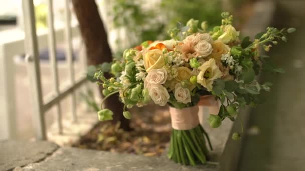 De bruiden boeket van rozen, lisianthus, en eucalyptus takjes staat bij de smeedijzeren hek — Stockvideo
