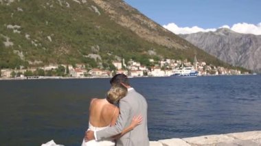Gelin ve damat rıhtımda oturup Perast 'e bakıyorlar. . 