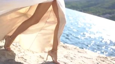 Beyaz elbiseli bir gelin iskelede yürüyor, etekleri rüzgarda dalgalanıyor. 