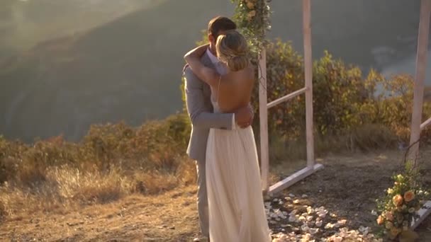 El novio abraza a la novia cerca del arco de la boda en el Monte Lovcen con vistas a la Bahía de Kotor — Vídeos de Stock