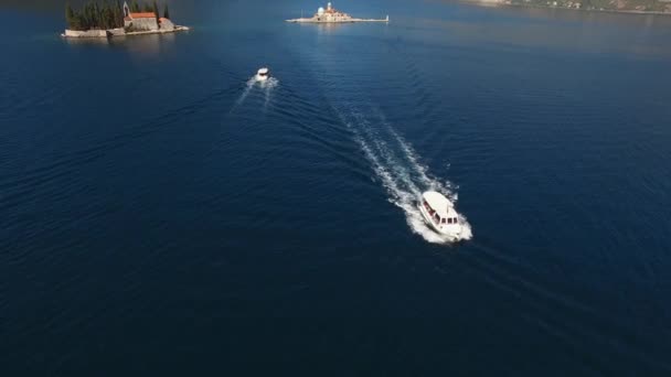 Het jacht en de boot varen vlak bij de eilanden in de baai van Kotor — Stockvideo