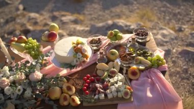Çerezler, meyveler, pembe bezle süslenmiş pasta, çiçekler ve mumlarla süslenmiş bir şamdan. 