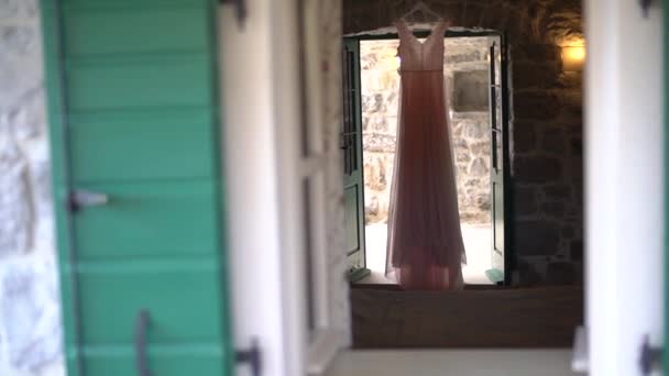 Ένα όμορφο απαλό ροζ νυφικό κρέμεται πάνω από την είσοδο σε ένα άνετο δωμάτιο με πράσινες πόρτες — Αρχείο Βίντεο