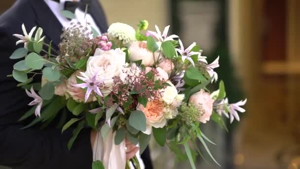 Le marié en costume tient un bouquet de la mariée — Video