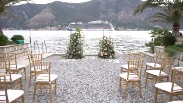 Svatební místo na břehu Kotorského zálivu, oblouk zdobený květinami a plachtami v dálce — Stock video