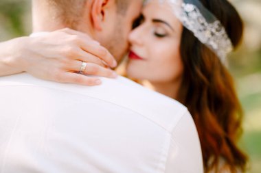 Gelin, parkta damadı nazikçe kucaklıyor ve gülümsüyor.