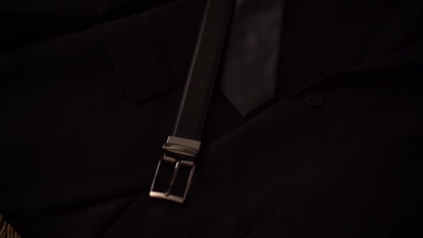 Cinturón de cuero, corbata y traje de novio se encuentran en la cama en el hotel durante la preparación para la ceremonia de boda — Vídeos de Stock