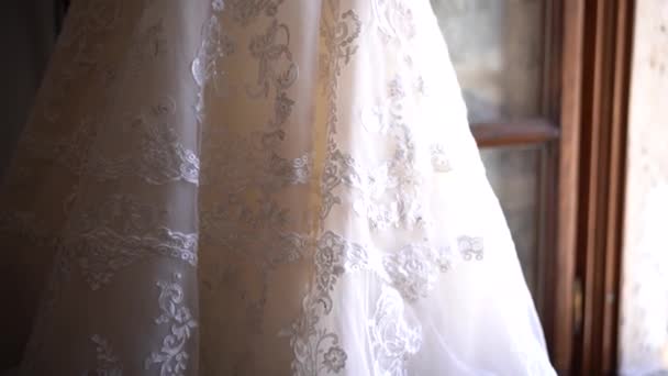 Belo vestido de noiva frisado pendurado perto da janela aberta — Vídeo de Stock