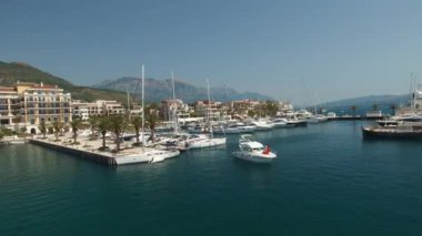 Porto Karadağ 'daki rıhtımın yakınındaki bir yatın pruvasında kırmızı elbiseli bir adam ve bir kadın duruyor.
