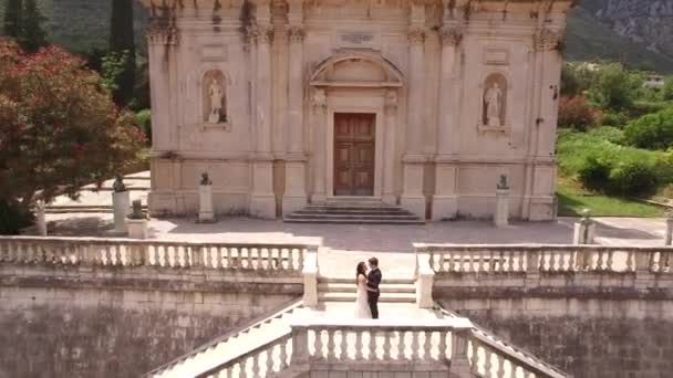 Braut und Bräutigam stehen eng umschlungen auf der antiken Treppe der Marienkirche — Stockvideo