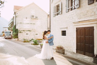 Gelin ve damat eski Perast kasabasındaki güzel beyaz evlerin yakınında kucaklaşıyorlar. 