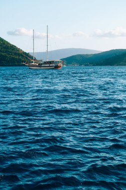 Yat, Perast şehrinin açıklarındaki dağların arka planına karşı mavi sularda süzülüyor..