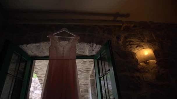 Koralikowy gorset bladoróżowej sukni ślubnej wiszącej nad wejściem, zbliżenie — Wideo stockowe