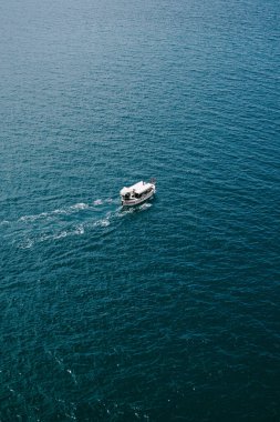 Küçük turist teknesi su dokusunda yüzüyor, helikopterden havadan görüntüler geliyor..