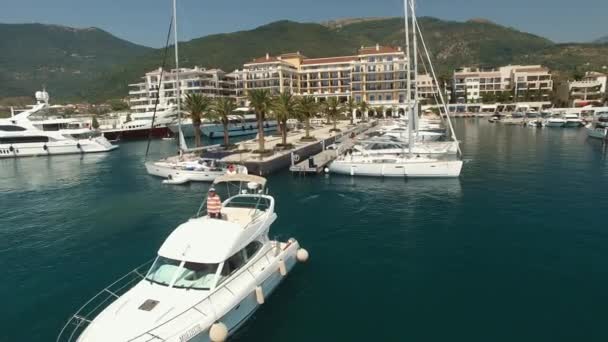 Seorang pria berdiri dan melihat keluar dari atap yacht meluncur dekat dermaga di Porto Montenegro — Stok Video