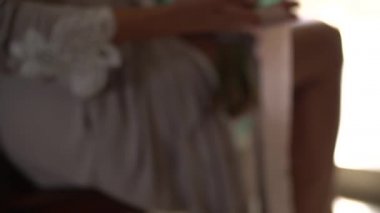 İpek bornozlu bir kadın kucağında bir buket tutuyor ve uzun kurdelelerle oynuyor.