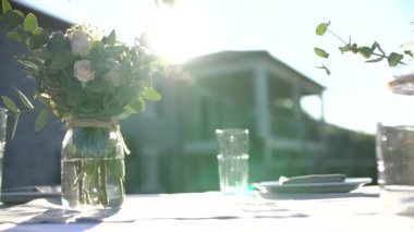 Düğün şöleninde masa, cam kavanozlarda mumlar ve villanın arka bahçesinde buketler. 