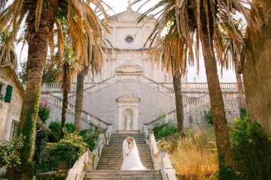  Gelin ve damat Prcanj 'daki Kutsal Bakire Meryem Kilisesi' nin merdivenlerinde el ele tutuşup el ele tutuşuyorlar.