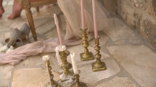 신부는 분홍색 의자에 앉아 있고, 그 옆에 는 여자의 신발 과 촛불을 켜고 있다 — 비디오