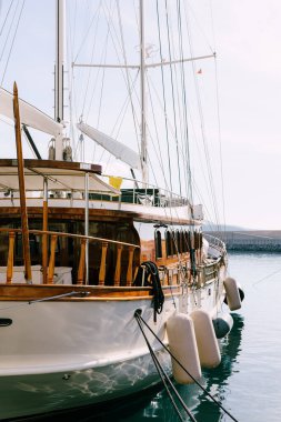Klasik ahşap yelkenli gemi. Yat kıyıya demir atmış. Kahverengi ahşap bir güvertede.