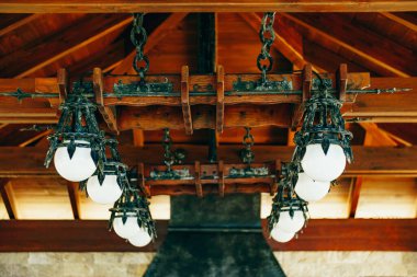 Yuvarlak beyaz topları olan büyük dövmeli demir bir avize. Şövalye tarzında metal kolye..