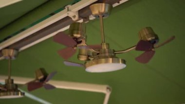 Yeşil tavanın altındaki vantilatör avizesi. Lambanın etrafında üç taraftar dönüyor..