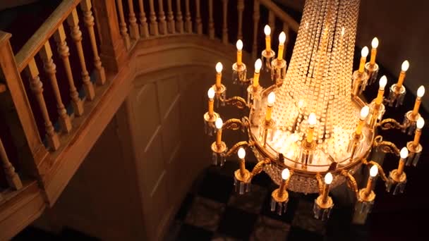 Gran lámpara de araña de cristal con colgantes y velas en una cadena bajo el techo. — Vídeos de Stock