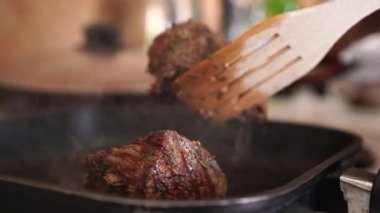 Eldivenli bir restoran şefinin yakın çekimi bifteği ızgaraya koyar. Bir aşçı, bir restorandaki ızgarada sulu bir et parçasını kızartır.. 