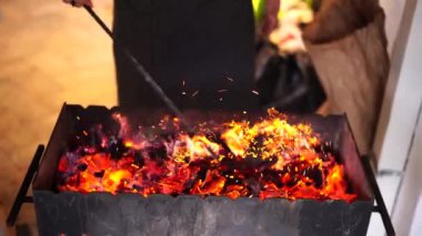 Aşçı Brezilya 'da yanan kömürü karıştırıyor. Aşçı ızgarayı yakar.