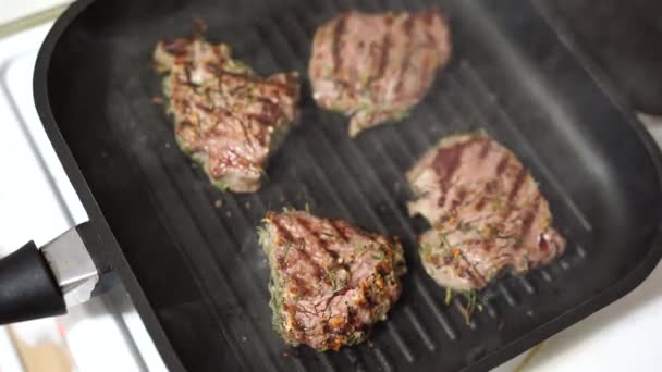 Čtyři opečené steaky na grilované pánvi, s jemně nasekanou rozmarýnem. — Stock video