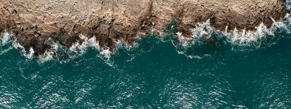 Wild ocean waters from above, waves hitting rocks - aerial photography.