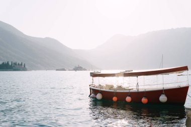 Kotor Körfezi 'nin suyunda güneşlenen zevk kırmızı motorlu tekne..