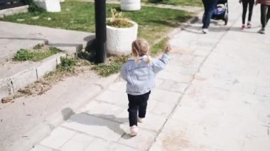 İki yaşında bir kız kaldırımda yürüyor..