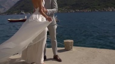 Gelin ve damat iskelede duruyor, gelinler rüzgârda çırpınıyor. 