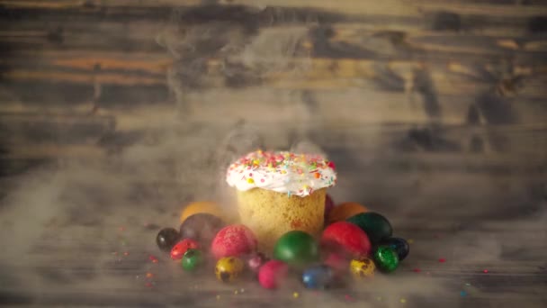 多色粉末、多色塗装鶏や木の背景にウズラの卵と白釉イースターケーキ。背景に白煙が広がる — ストック動画