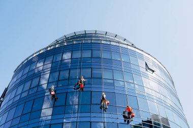 Pencere temizleyicileri binanın dışındaki mavi aynalı pencereleri yıkıyor..