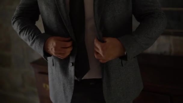 Egy szürke öltönyös férfi kiegyenesíti és begombolja a kabátját. — Stock videók
