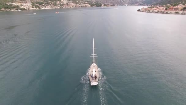 A sailing yacht sails on the Bay of Kotor around the beautiful old towns — Stock Video