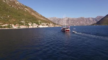 Kotor Körfezi 'nin ortasında bir yat ve tekneler açılır. Önünde de sıcak kasabanın yakınında bir dağ vardır.