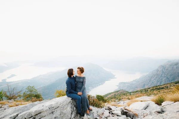 Die Braut und der Bräutigam, die sich auf dem Lovcen-Berg hinter ihnen umarmen, eröffnen einen Blick auf die Bucht von Kotor — Stockfoto